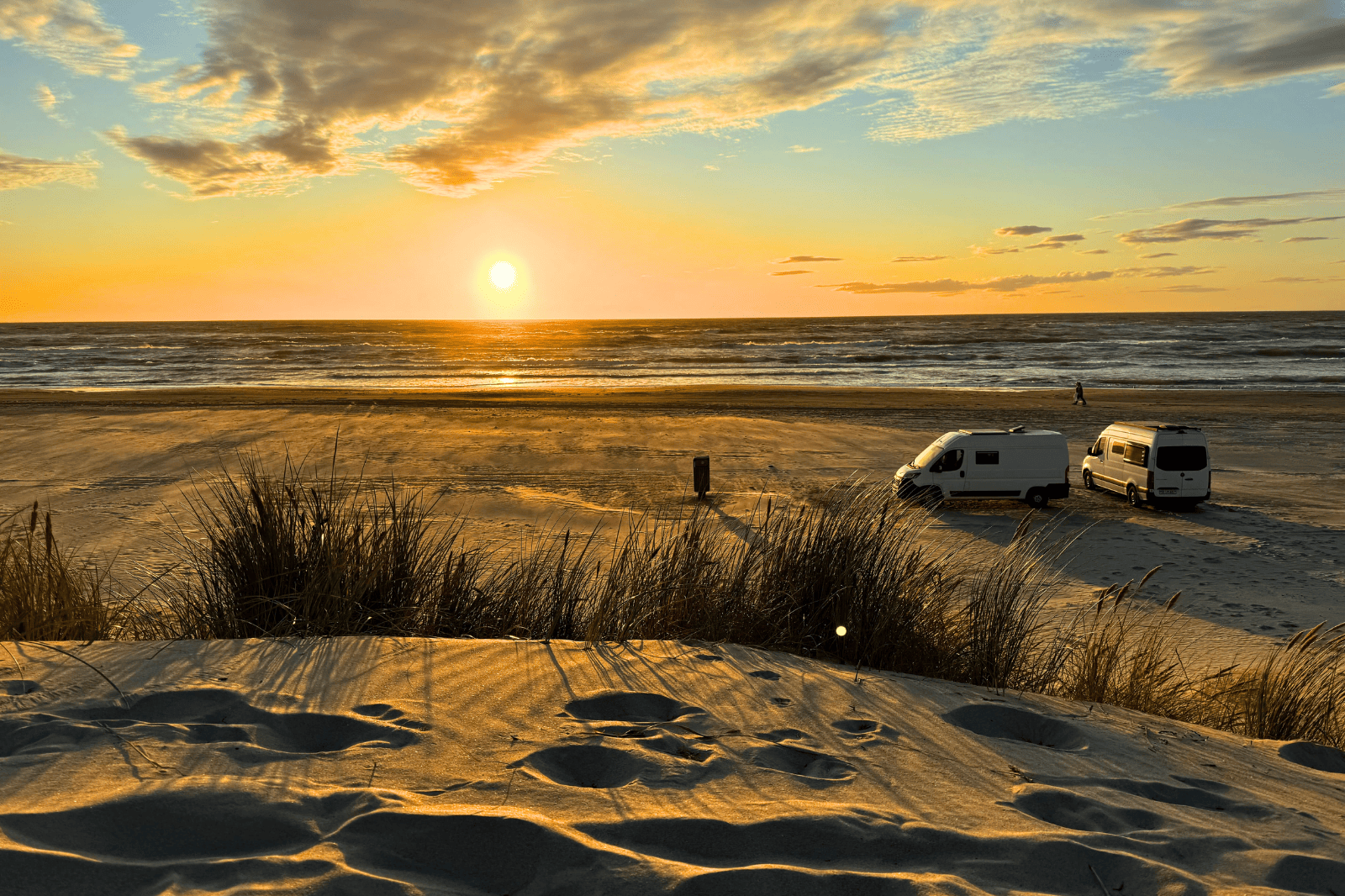 Zwei Campervans stehen auf einem Strand im Sonnenuntergang