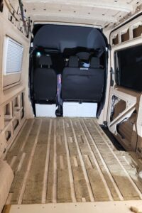 Der Boden eines noch leeren Campervans wird mit Schafwolle gedämmt