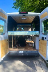 Blick auf das Querbett in einem Campervan Peugeot Boxer mit Holzlatten