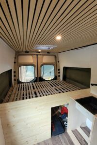 Blick auf das Querbett in einem Campervan mit Lattenrost