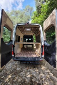 Blick auf das Querbett in einem Campervan mit Lattenrost